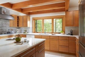 Kitchen with wood cabinetry, tiling flooring, and a pair of casement windows positioned over kitchen sink.