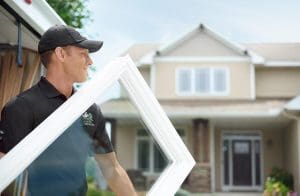 RBA window technician carrying picture window into home for installation.