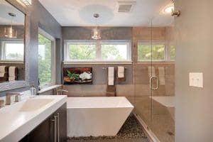 View of sleek bathroom with standalone bathtub stationed under a white-frame awning window overlooking yard.