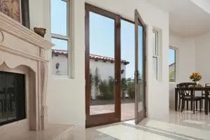 Do French Doors Increase Home Value? | RBA of Greater Wisconsin Living room with fireplace in corner and two wood-frame French patio doors leading outside.