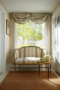 Elegant home interior with rug, love seat, and small coffee table. Large double-hung window overlooking scenic landscape.