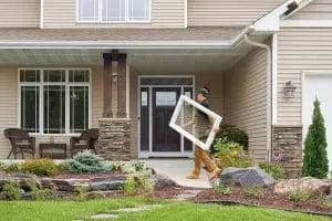 RbA craftsman is carrying a picture window into a home for installation.