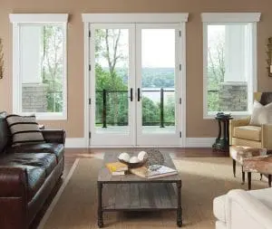 Living room with wood flooring, brown leather couch, and white French patio doors.