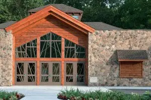 Cabin-style home with large specialty shaped windows.