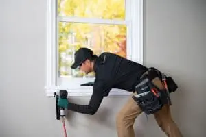 RBA window technician installing white trim around double hung window.
